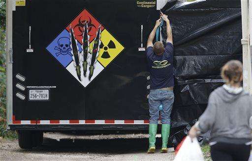 A hazmat worker puts up a plastic sheet before starting to clean the apartment building of a hospital worker, Sunday, Oct. 12, 2014, in Dallas. Top federal health officials said that the Ebola diagnosis in a health care worker who treated Thomas Eric Duncan at a Texas hospital clearly indicates a breach in safety protocol. (AP Photo/LM Otero)