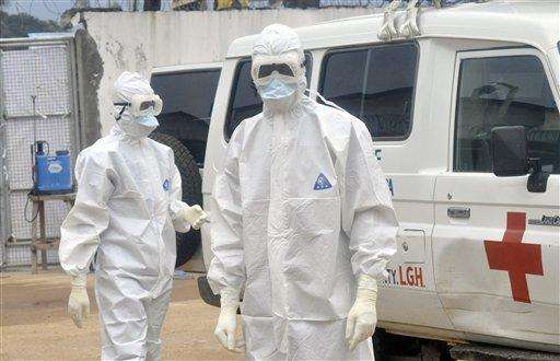 Health workers wearing protective gear wait to carry the body of a person suspected to have died from Ebola, in Monrovia, Liberia, Monday Oct. 13, 2014. Some nurses in Liberia defied calls for a strike on Monday and turned up for work at hospitals amid the worst Ebola outbreak in history. In view of the danger of their work, members of the National Health Workers Association are demanding higher monthly hazard pay. The association has more than 10,000 members, though the health ministry says only about 1,000 of those are employed at sites receiving Ebola patients. (AP Photo/Abbas Dulleh)