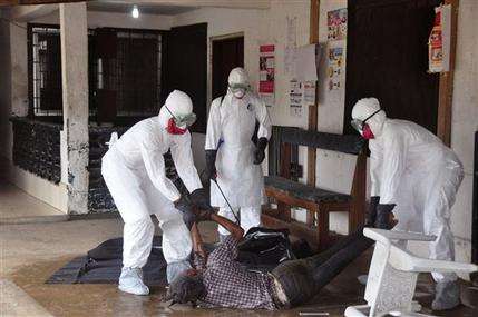 Health workers in protective gear move the body of a person that they suspect dyed form the Ebola virus in Monrovia, Liberia, Tuesday, Sept. 16, 2014. The number of Ebola cases in West Africa could start doubling every three weeks and it could end up costing nearly $1 billion to contain the crisis, the World Health Organization warned Tuesday. (AP Photo/Abbas Dulleh)