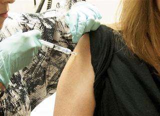 Caption: This handout file photo taken Sept. 2, 2014, provided by National Institute of Allergy and Infectious Diseases (NIAID) shows a 39-year-old woman, the first participant enrolled in VRC 207, receiving a dose of the investigational NIAID/GSK Ebola vaccine at the National Institute of Health (NIH) Clinical Center in Bethesda, Md. The hope is that the first human safety study of the vaccine might eventually be used in the current Ebola outbreak in West Africa. New monkey studies show that one shot of an experimental Ebola vaccine can trigger fast protection, but the effect waned unless the animals got a booster shot made a different way. (AP Photo/NIAID, File)