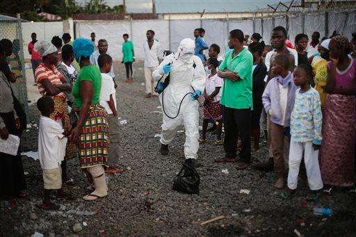  
              FILE - In this Sept. 30, 2014, file photo, a  medical worker sprays people being discharged from the Island Clinic Ebola treatment center in Monrovia, Liberia. (AP Photo/Jerome Delay, File)
             