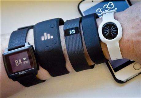 Fitness trackers, from left, Basis Peak, Adidas Fit Smart, Fitbit Charge, Sony SmartBand, and Jawbone Move, are posed for a photo next to an iPhone, Monday, Dec. 15, 2014, in New York. (AP Photo/Bebeto Matthews)